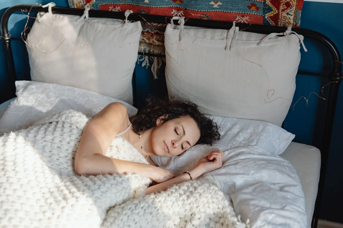 Does 8 Sleep work in winter? Woman sleeping warm under a wool blanket on a cold night